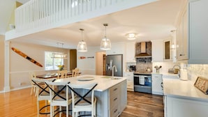 Una cocina amplia con una isla grande, suelo de madera e iluminación colgante.