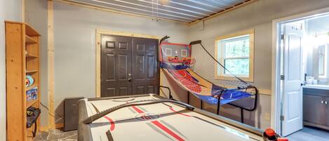 A room with a pool table, a ceiling fan, and a door leading to another room.