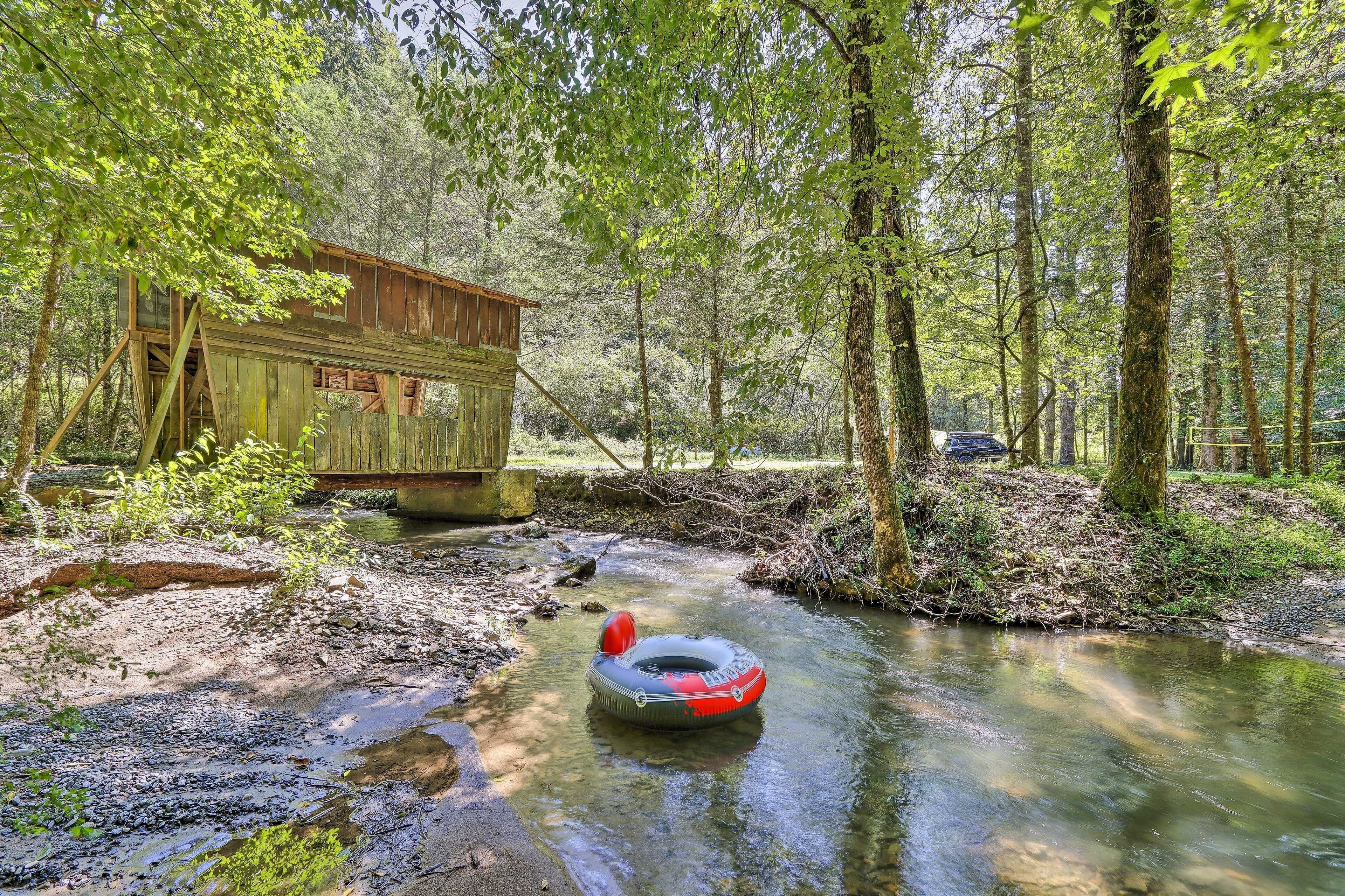 A rustic wooden cabin by a forest stream with a raft.
