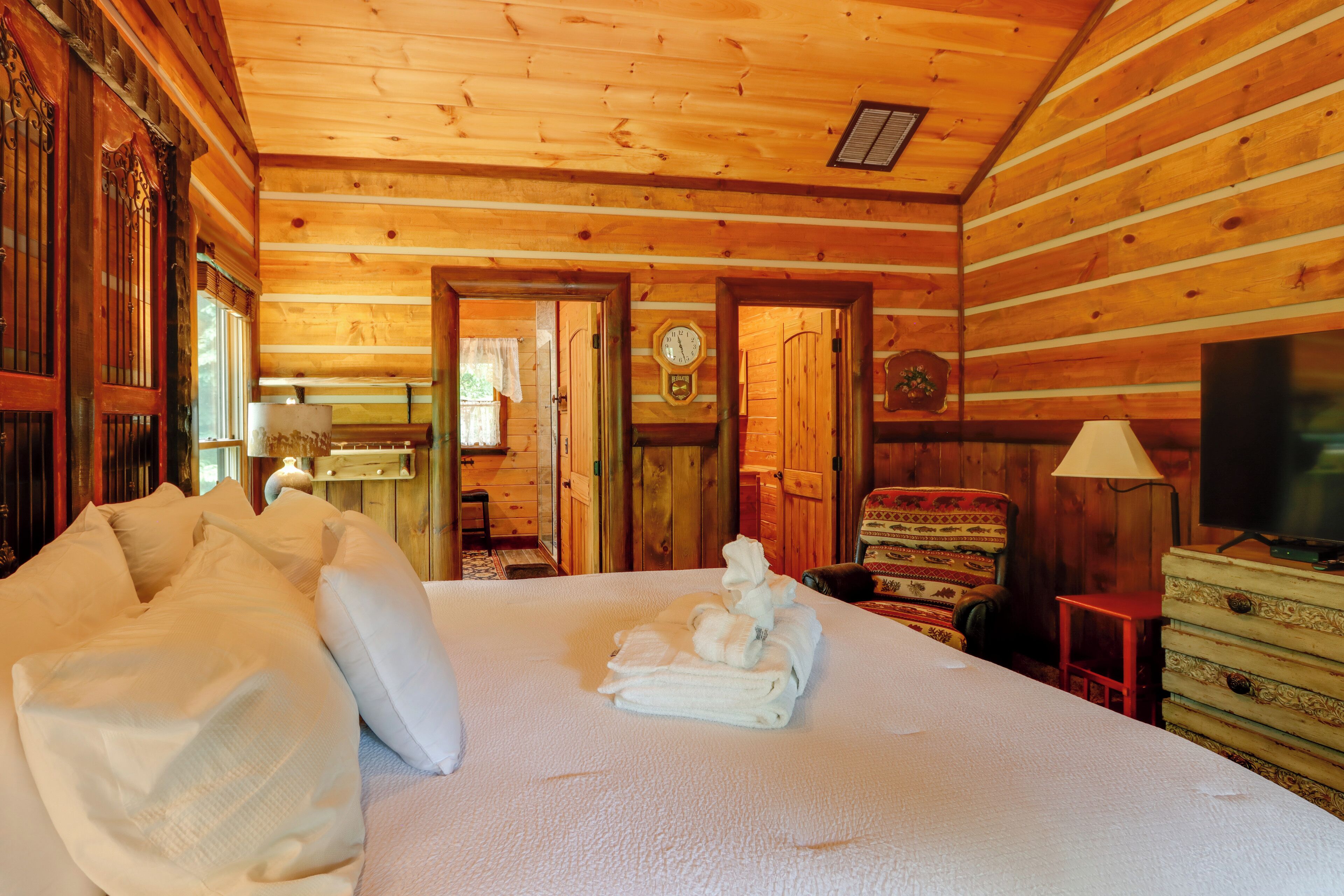 Une chambre rustique en bois, avec un lit, un téléviseur et une horloge au mur.