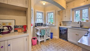 A compact kitchen with white cabinets, a microwave, a toaster, and a coffee maker. There are two windows providing natural light, and a dishwasher is visible. - 1 Mi to Park & Waterfront! Seattle Home w/ Balcony (Seattle)