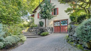 A house with a stone staircase leading to a red door, surrounded by lush greenery and a paved driveway. - 1 Mi to Park & Waterfront! Seattle Home w/ Balcony (Seattle)