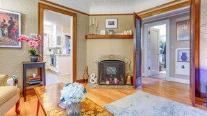 A cozy living room with a fireplace, wooden furniture, and a view into another room. - 1 Mi to Park & Waterfront! Seattle Home w/ Balcony (Seattle)