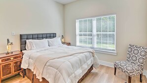 A bedroom with a bed, a nightstand, a chair, and a window with blinds. - Cozy Tennessee Country Retreat on 5 Acres! (Pegram)