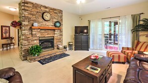 Ein Wohnzimmer mit Kamin aus Stein, einem Fernseher und einer Sitzecke mit gestreiften Sofas.