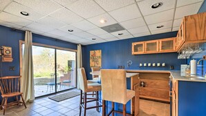 A kitchen with wooden cabinets, a bar area, and a dining space with chairs. - Lakefront Macon Getaway w/ Stunning Boathouse (Macon)