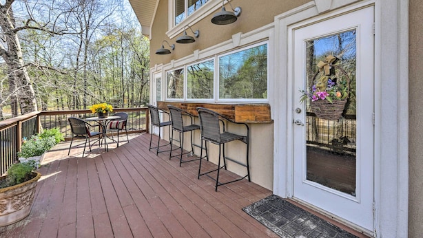 A deck with outdoor seating, a wooden bar, and a door with a decorative basket. - Cozy Creekside Cabin w/ Grill: Fish & Explore! (Thomaston)