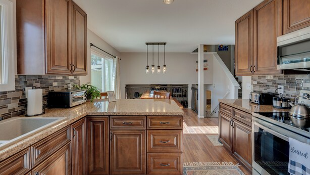 A modern kitchen with wooden cabinets, granite countertops, and stainless steel appliances. - Loveland Home w/ Private Hot Tub + Wood Fireplace! (Loveland)