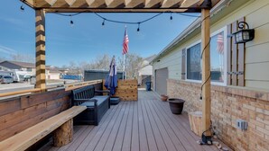 A wooden deck with benches, a pergola, and an American flag. - Loveland Home w/ Private Hot Tub + Wood Fireplace! (Loveland)