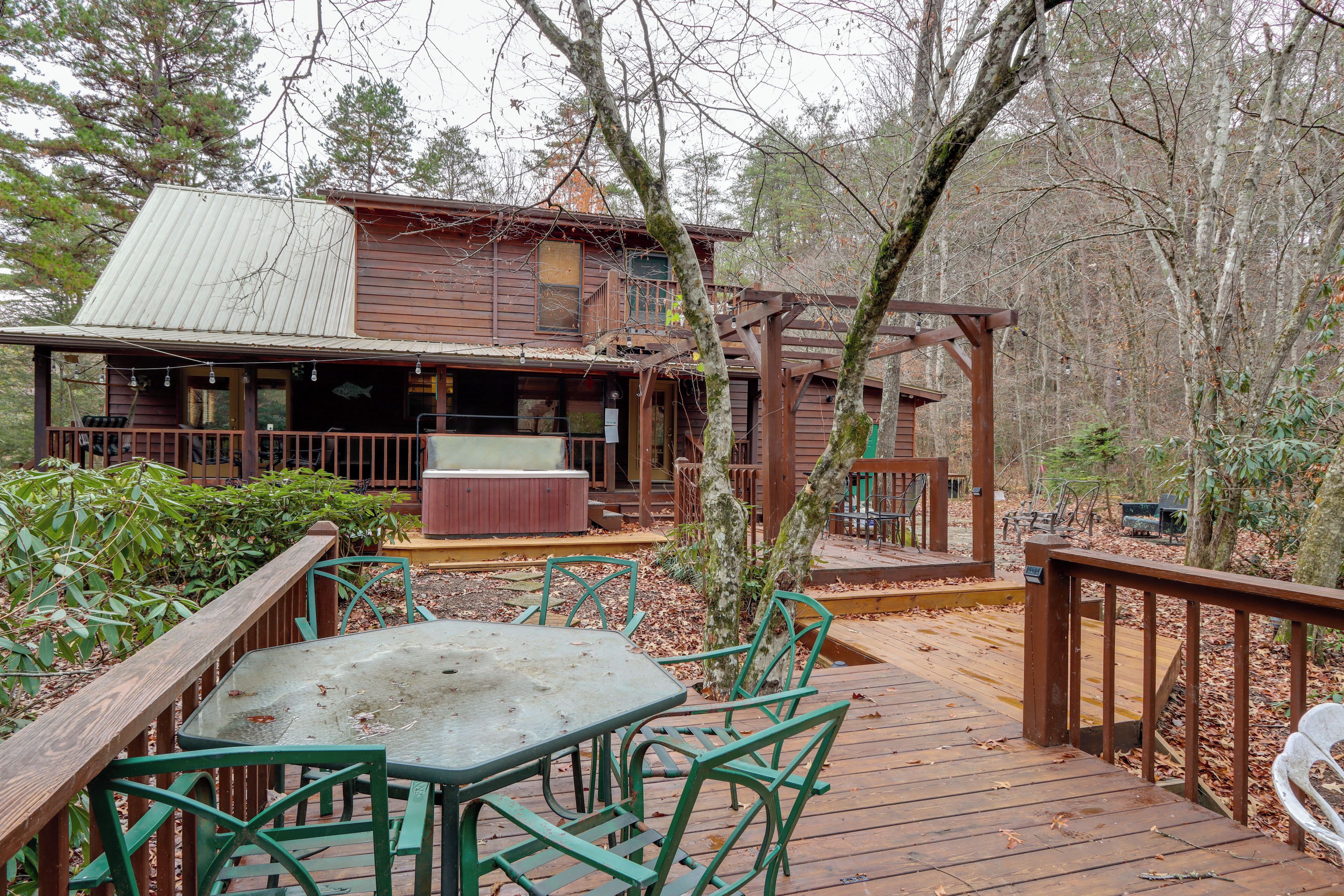 A wooden cabin with a deck, outdoor seating, and a hot tub.