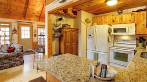 A kitchen with wooden cabinets, a granite countertop, a refrigerator, a microwave, and an oven.