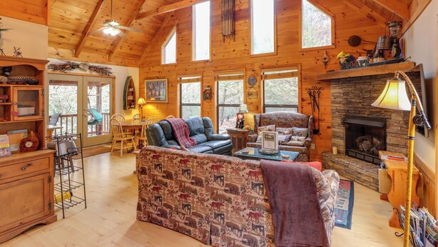 A cozy cabin interior with a fireplace, wooden walls, and a large window.