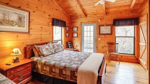 A wooden cabin bedroom with a bed, nightstand, dresser, and a chair.