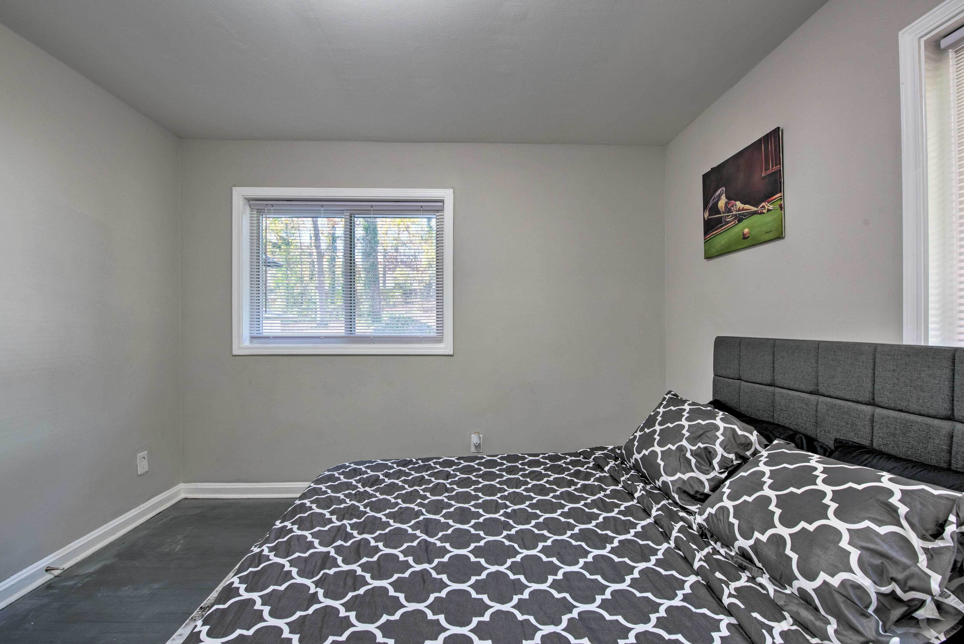 A bedroom with a bed, a window, and a painting on the wall.