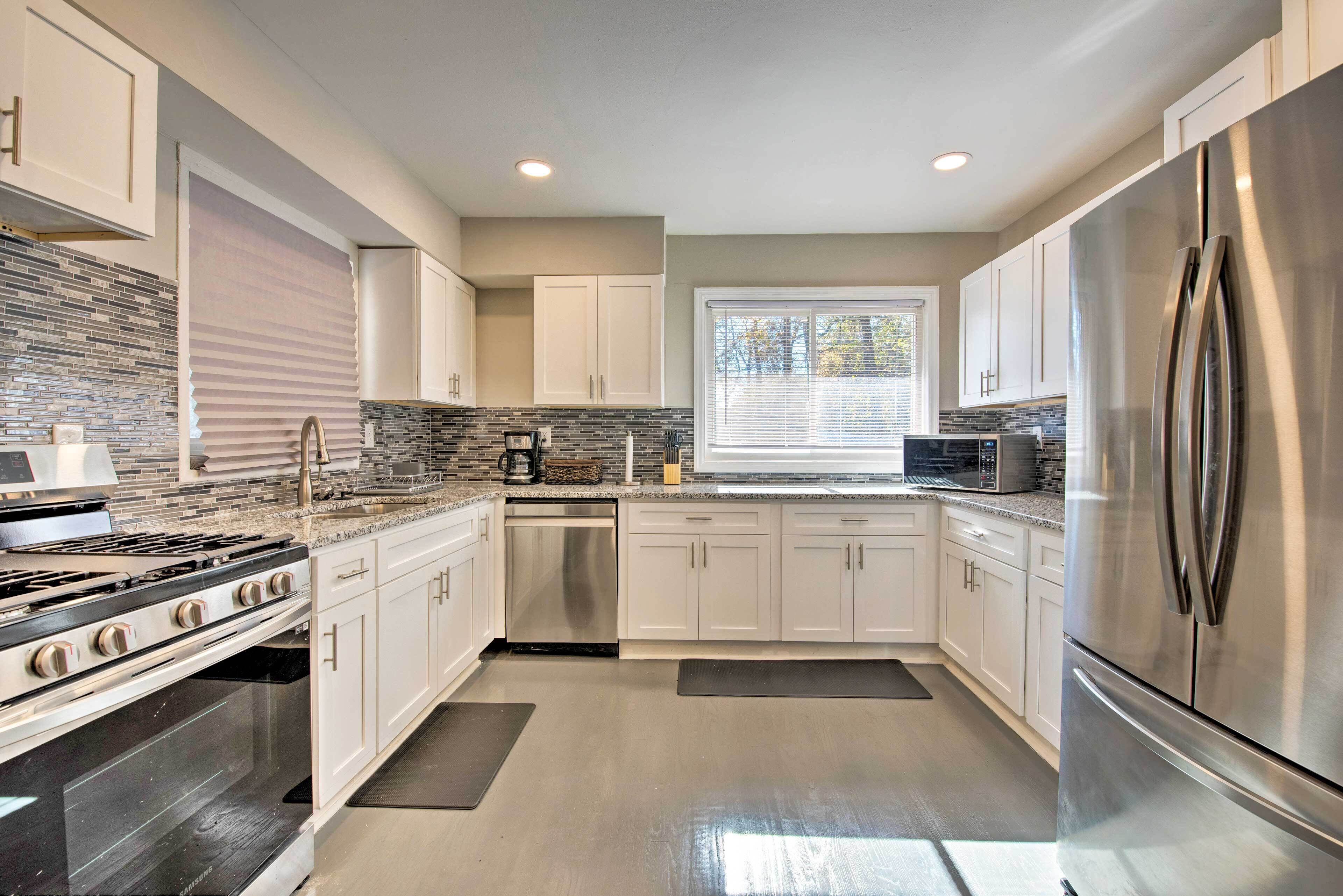 A modern kitchen with stainless steel appliances, white cabinets, and a tiled backsplash.