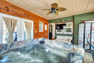 Habitación con jacuzzi, paredes de madera, ventilador de techo y vistas al exterior.