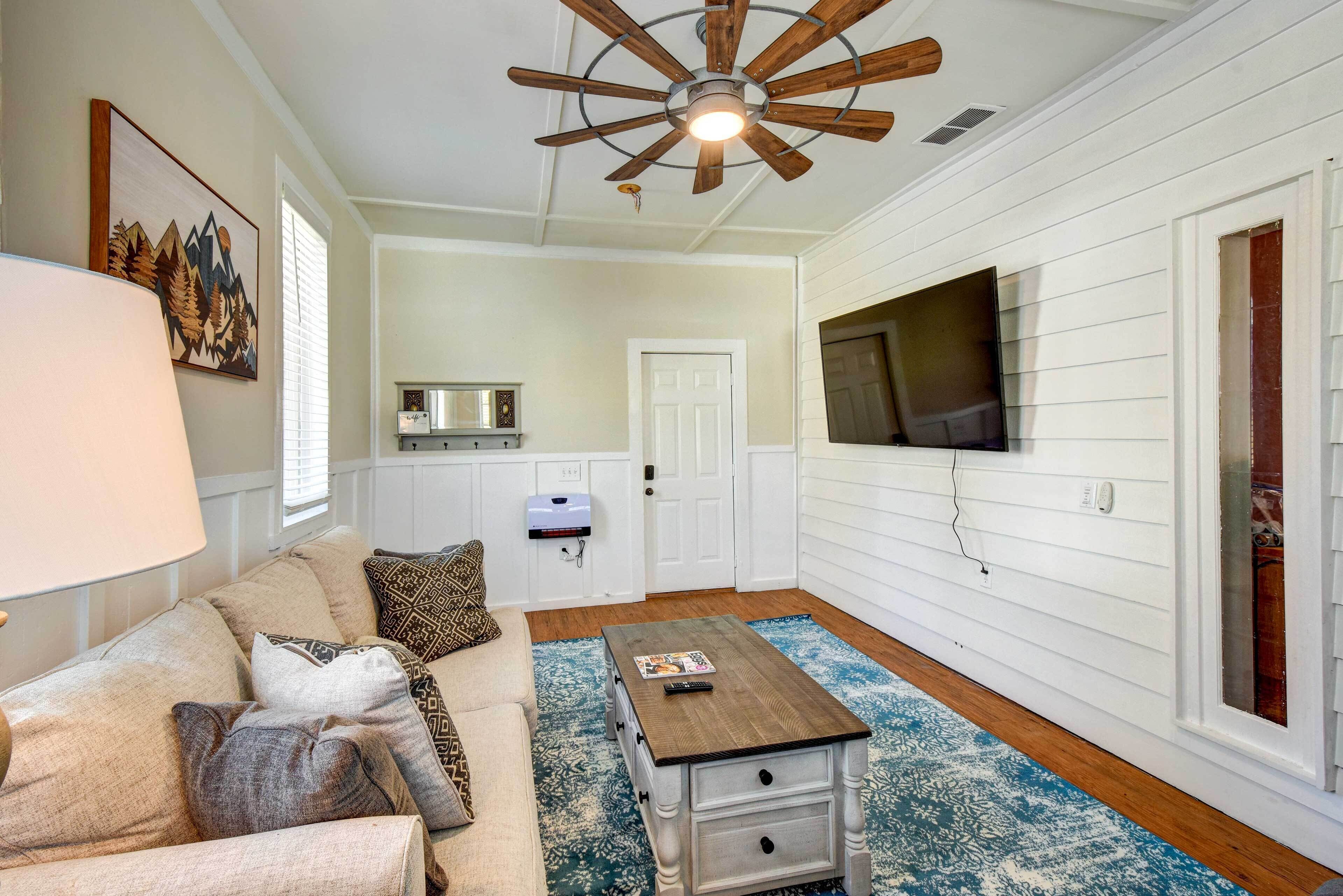 Un salon chaleureux avec une table basse en bois, un canapé beige et un ventilateur de plafond.