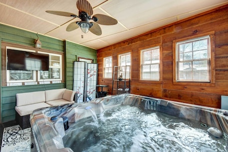 A hot tub in a room with wooden walls and large windows.