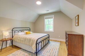 A bedroom with a bed, bedside table, lamp, window, dresser, and a patterned rug. - Spacious Lake Sinclair Vacation Rental w/ Dock! (Milledgeville)