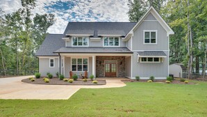 A two-story house with a front porch, a stone entryway, and a driveway leading to the garage.
