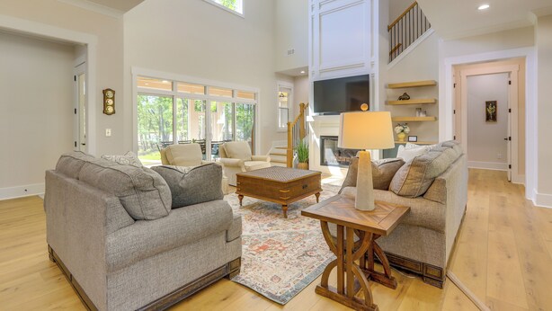A spacious living room with two grey sofas, a wooden coffee table, and a large TV.