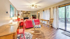 A spacious living room with a fireplace, red furniture, and a large window.
