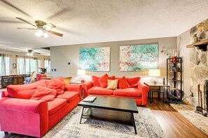 A living room with a red sofa set, a coffee table, and a fireplace. There are two abstract paintings on the wall and a ceiling fan. - Artist's Retreat at Sky Valley w/ Balcony & Deck (Dillard)