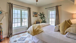 Un dormitorio con cama, ventilador de techo y ventana con cortinas.
