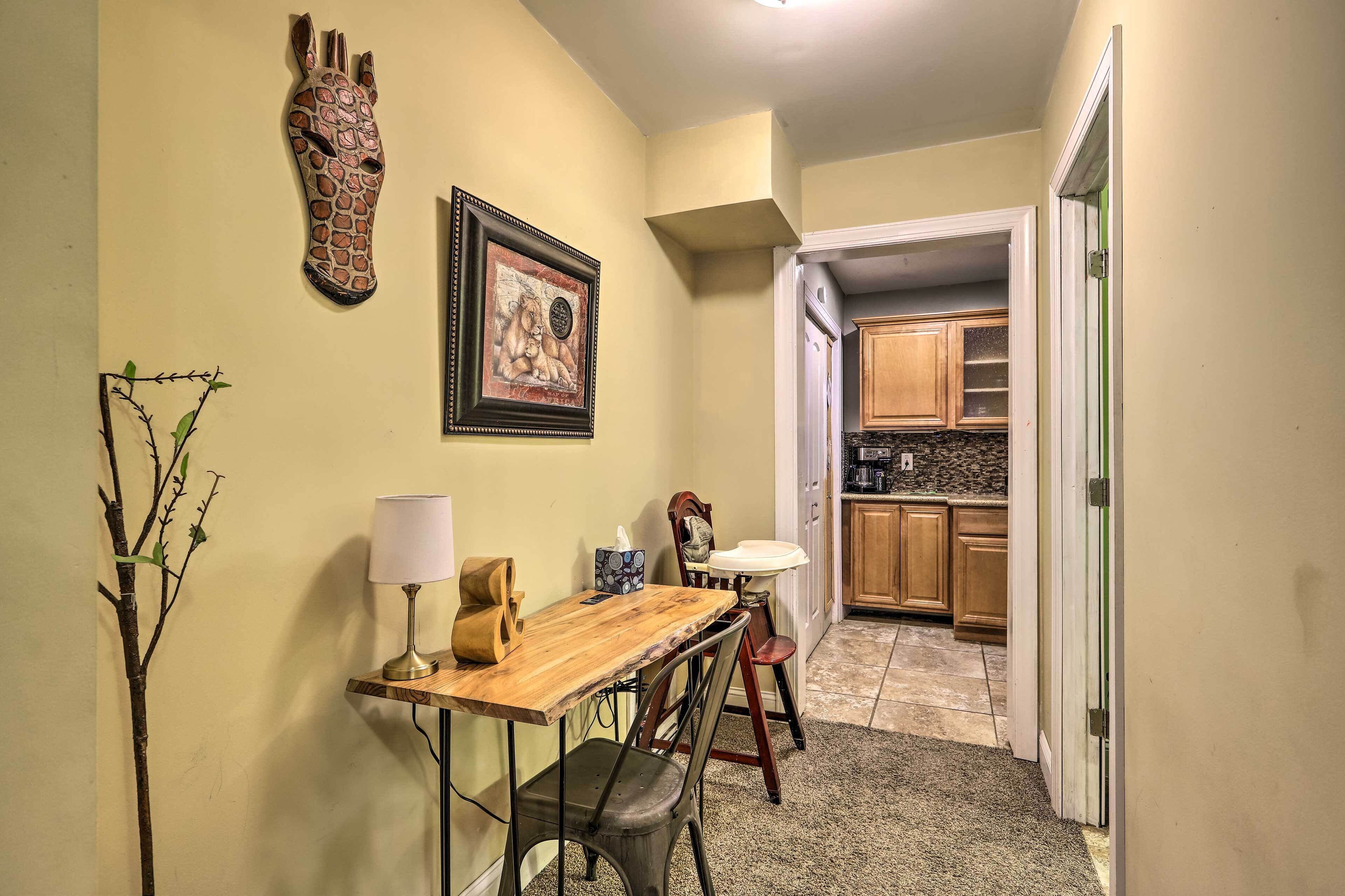 A compact kitchen with wooden cabinets, a granite countertop, and a small dining area with a wooden table and metal chairs.