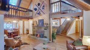 Amplio espacio tipo loft con chimenea, pisos de madera y un alto techo con vigas a la vista.
