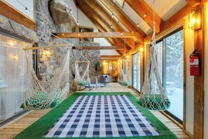 A cozy interior with a checkered floor, hanging hammocks, and a stone wall. - Riverside Colorado Cabin w/ Deck & Hot Tub (Dumont)