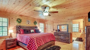 A wooden cabin bedroom with a bed, dresser, and a ceiling fan. - Hot Tub & Game Room: Blue Ridge Getaway (Blue Ridge)
