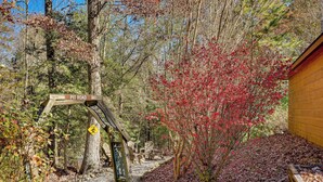 A wooden signpost labeled 'Pit Road' in a forested area with a wooden building and a path covered with fallen leaves. - Hot Tub & Game Room: Blue Ridge Getaway (Blue Ridge)