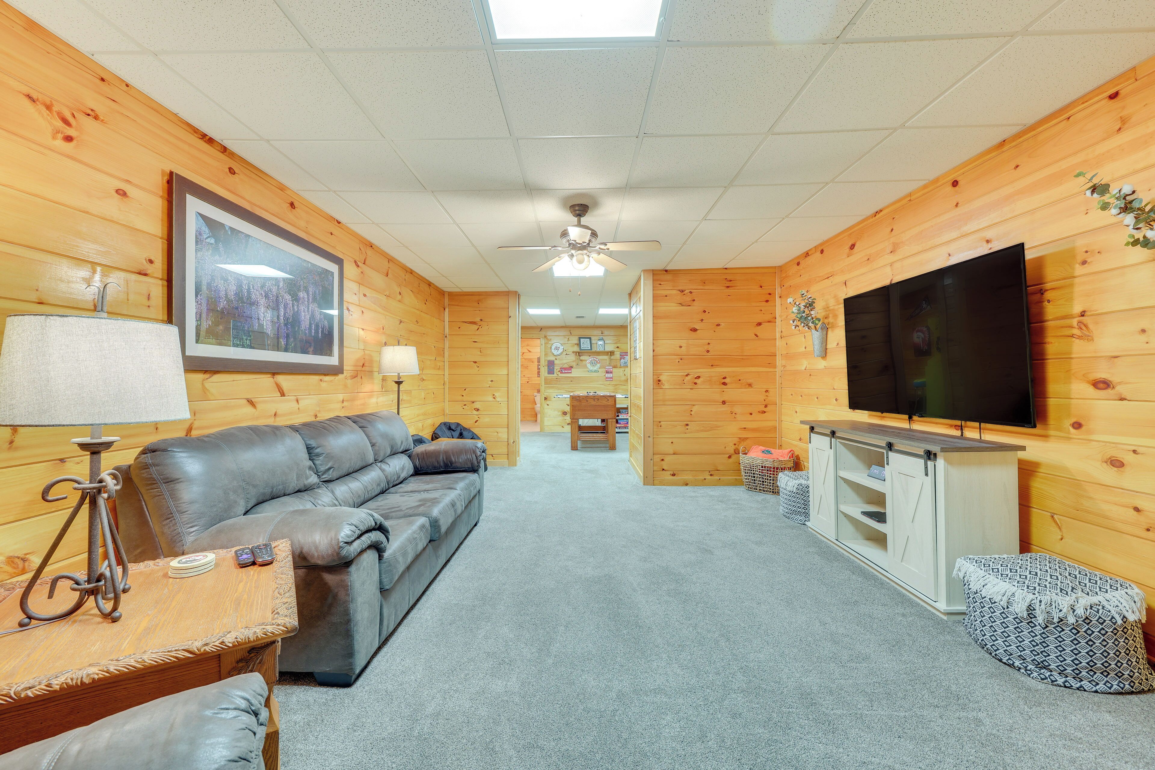 A cozy room with a leather sofa, a TV, and a ceiling fan.