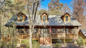 A wooden cabin with a porch, a flag, and a small garden area. - Hot Tub & Game Room: Blue Ridge Getaway (Blue Ridge)