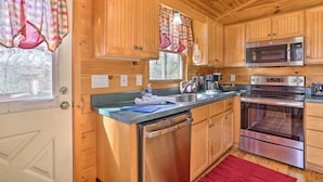A wooden cabin kitchen with a stainless steel dishwasher, oven, and microwave. - 'serenity Cabin' w/ Furnished Deck (Mineral Bluff)