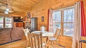 A cozy cabin interior with a wooden ceiling, a round dining table with chairs, a sofa, and a television. - 'serenity Cabin' w/ Furnished Deck (Mineral Bluff)