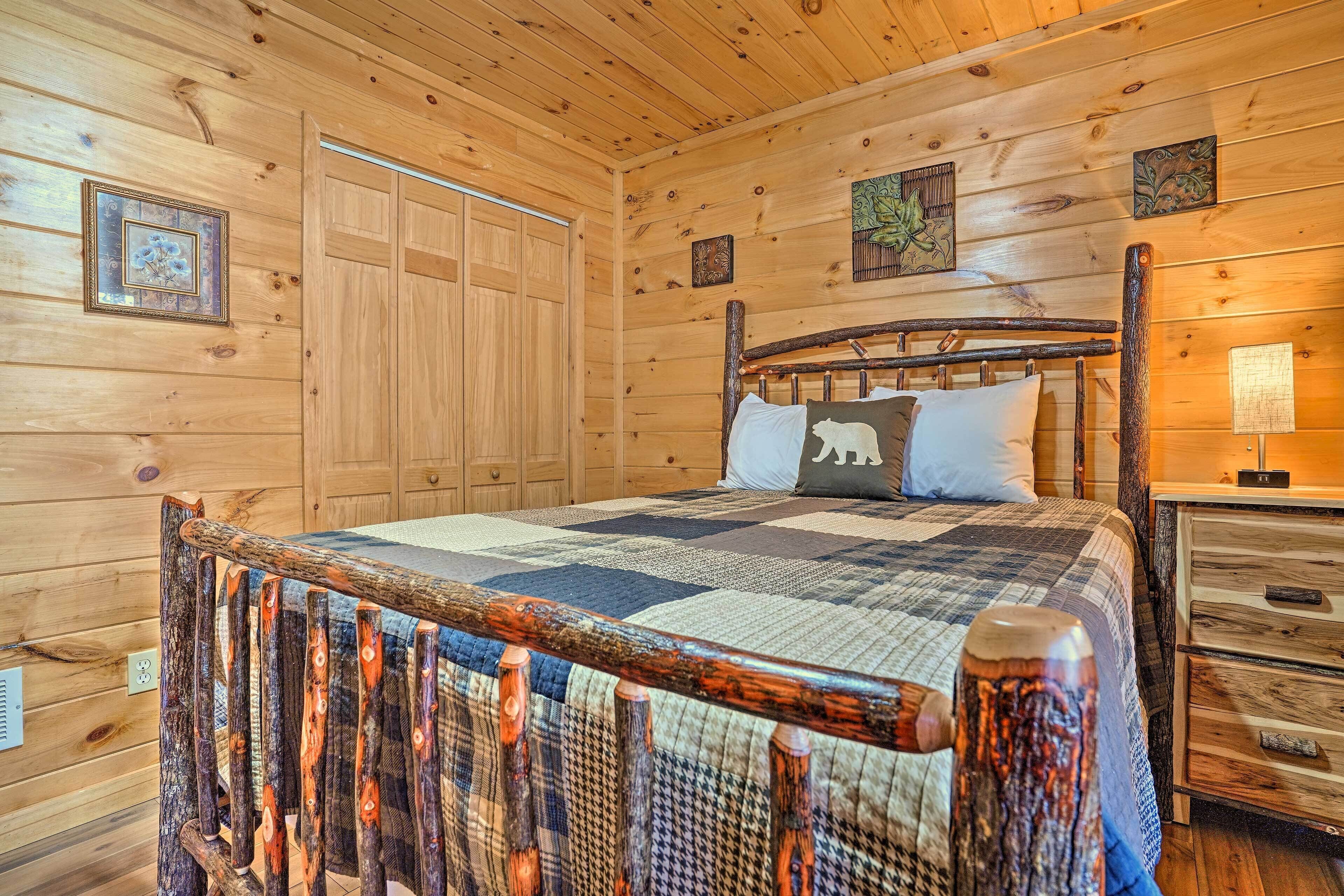 A wooden cabin bedroom with a large bed, a wooden headboard, a nightstand, and a quilt.
