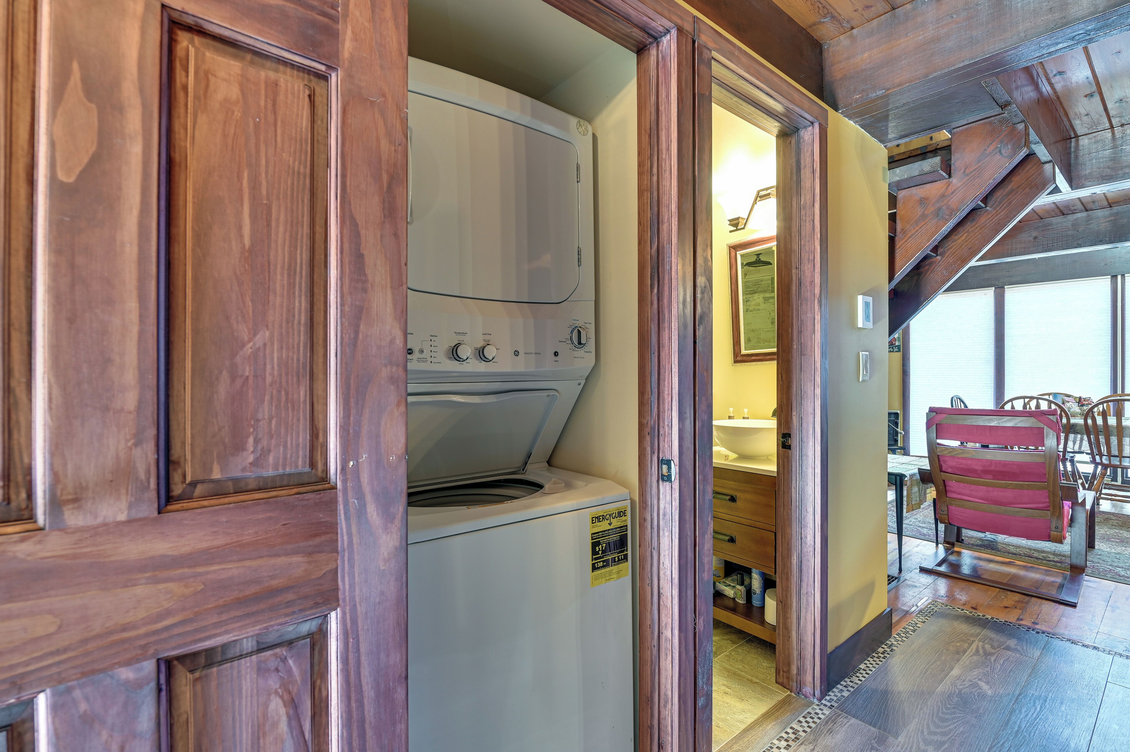 A laundry room with a washer and dryer, wooden walls, and a dining area with chairs.