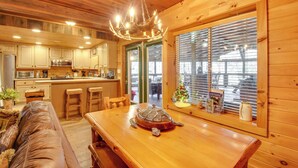 A wooden cabin interior with a dining table, a leather couch, and a turtle sculpture. - Riverfront Helen Cabin w/ Hot Tub & Deck! (Helen)