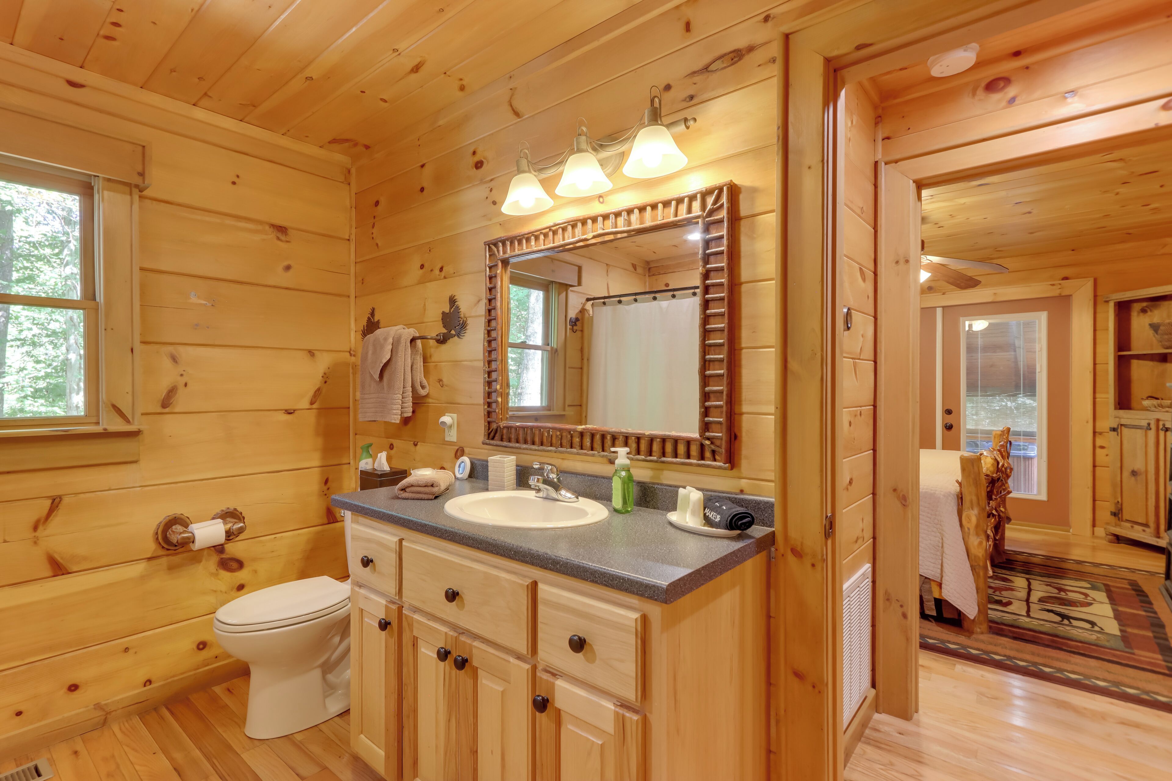 A wooden cabin bathroom with a sink, toilet, and mirror.