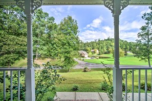 A gazebo with a view of a green landscape, including a golf course and a house.