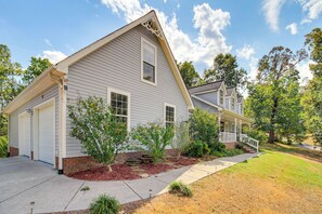 A two-story house with a garage, a covered porch, and a well-maintained lawn.