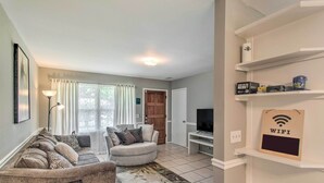 Una sala de estar con sofá, sillón y mueble para televisión.