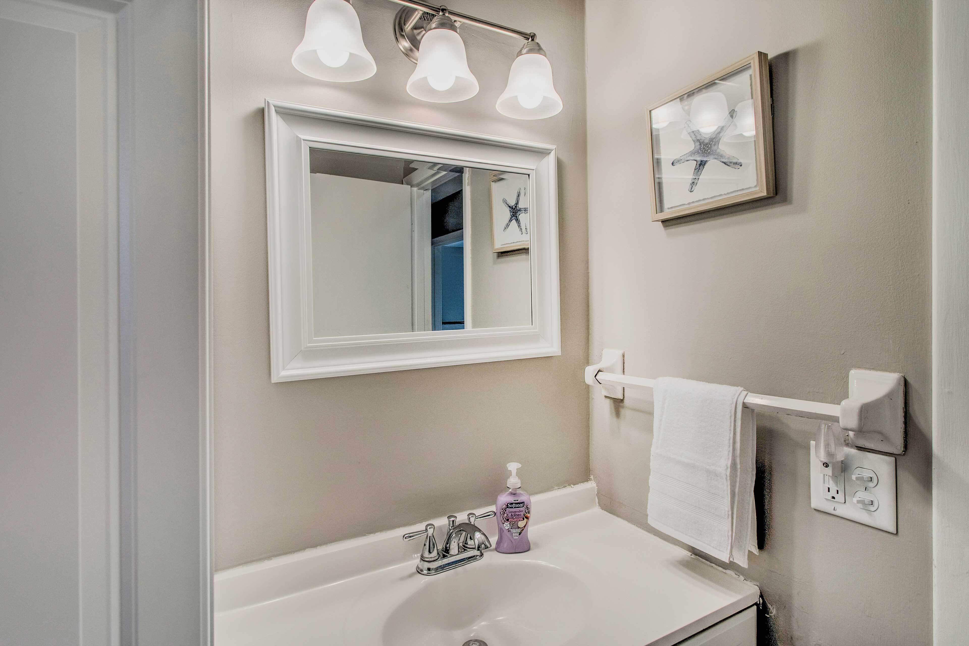 A bathroom with a white sink, a mirror, a towel rack, and a framed picture on the wall.