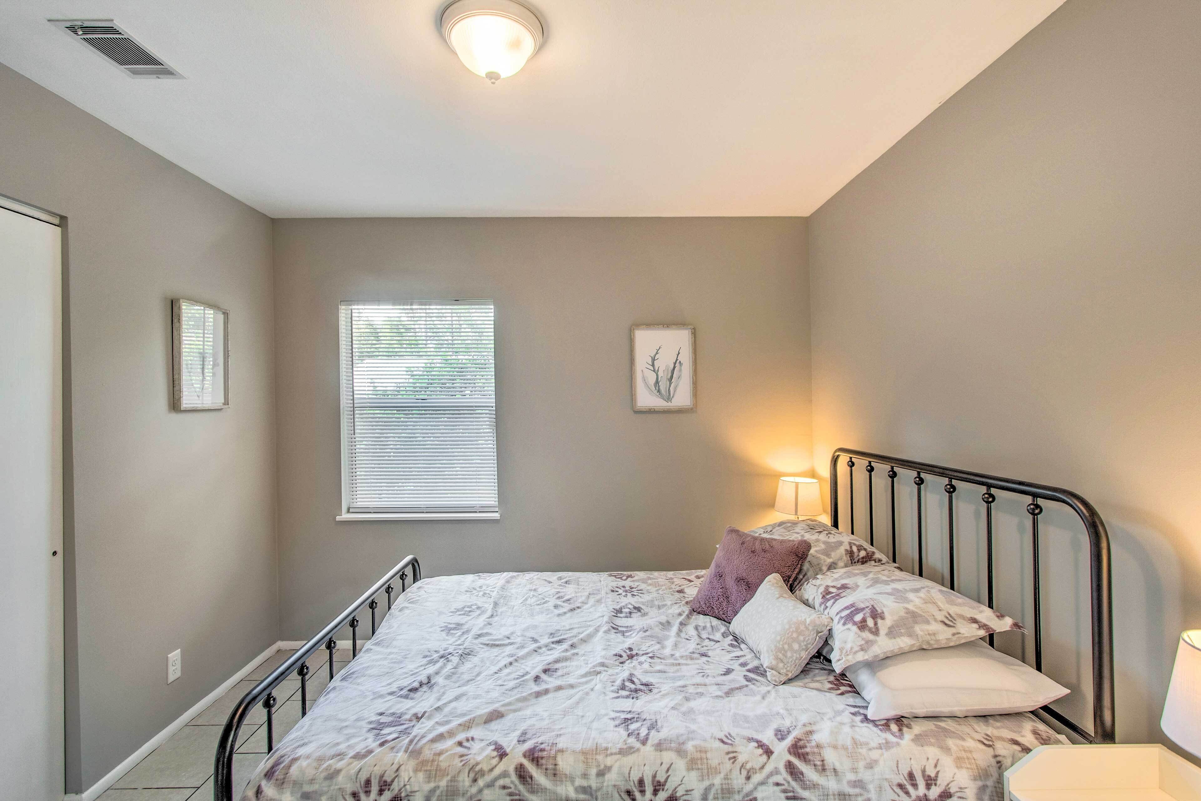 A bedroom with a bed, a window, and a wall-mounted light fixture.