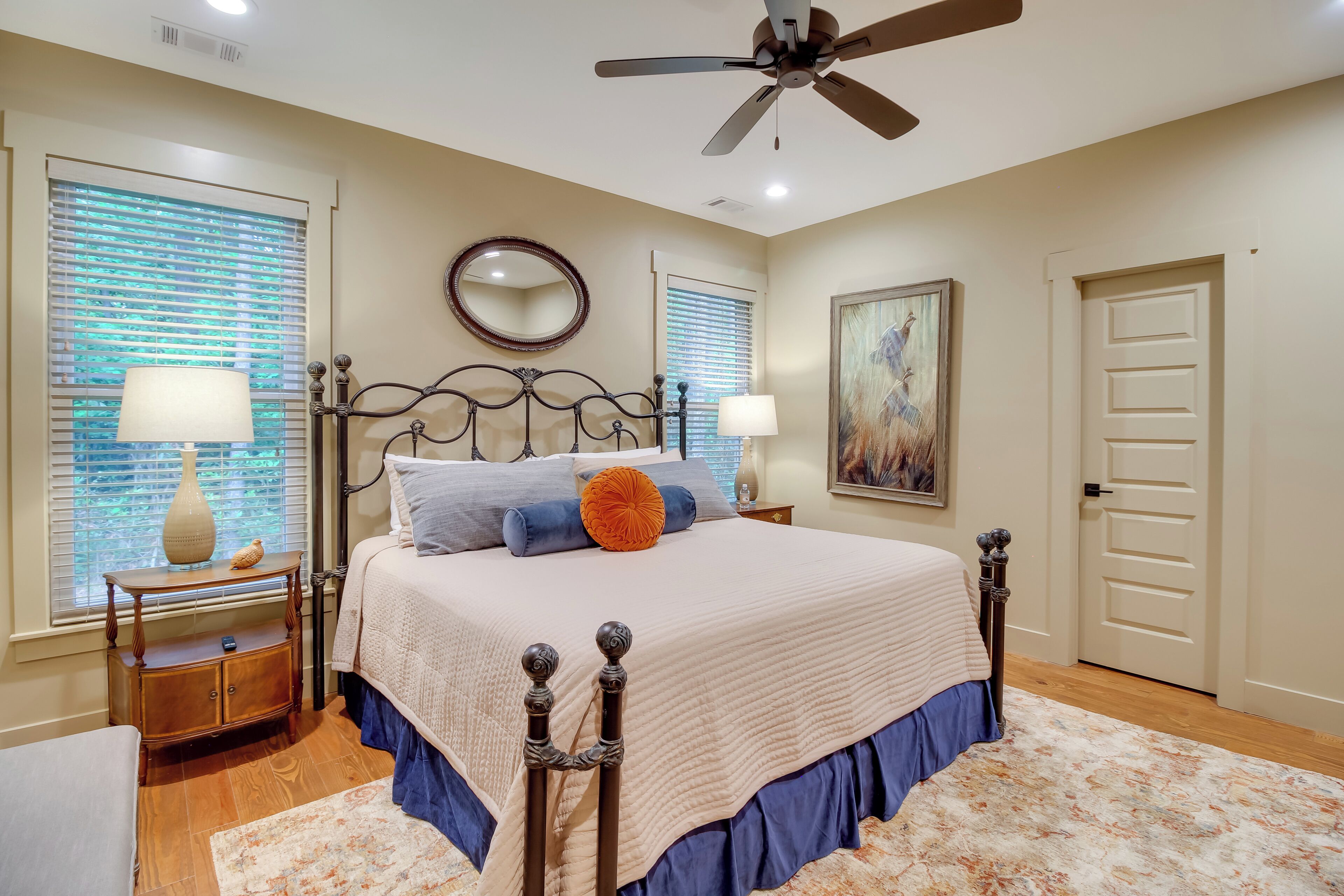 A bedroom with a bed, two bedside tables, a ceiling fan, and a door.