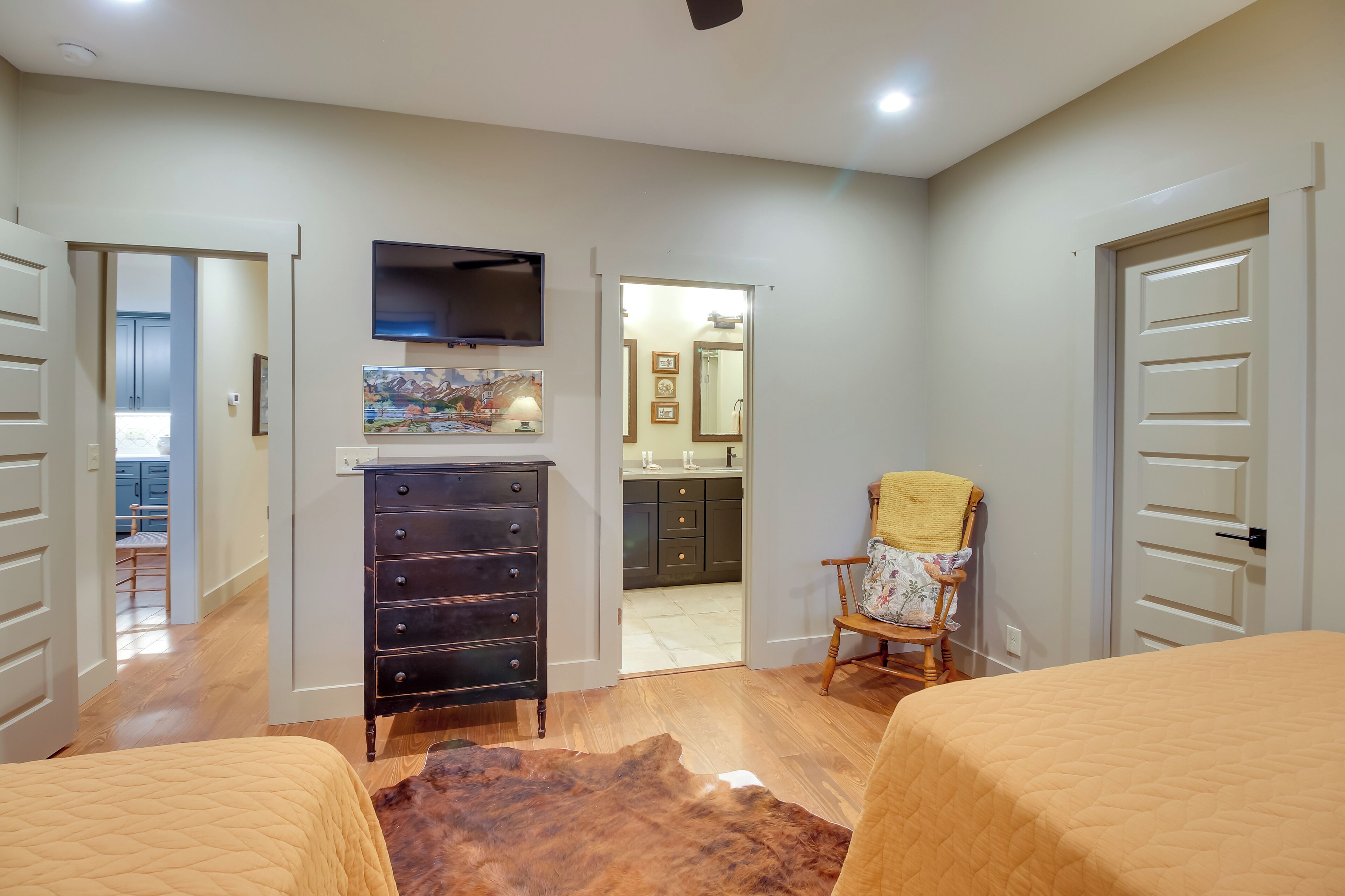 A bedroom with two beds, a dresser, a TV, and a chair.