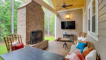Relax in this serene outdoor space with a brick fireplace, comfortable seating, and a flat-screen TV.