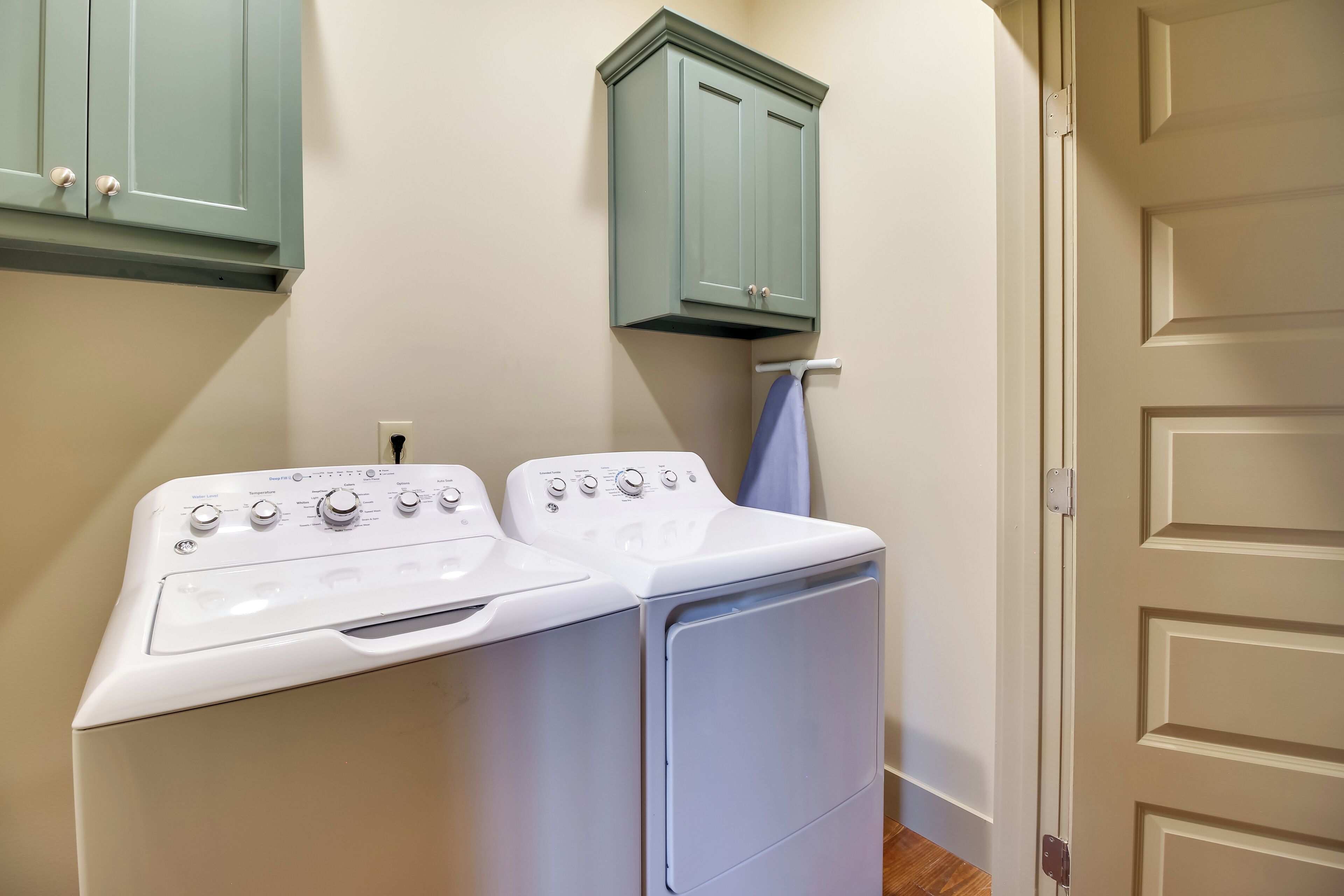 A laundry area with two washing machines and a cabinet.